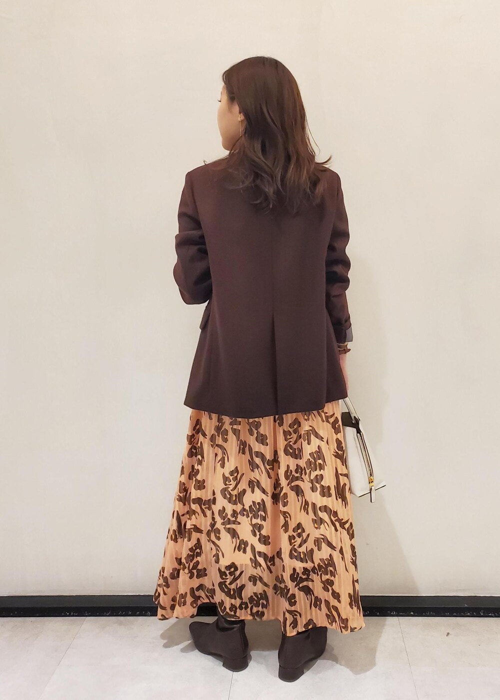 グレー系のハンドバッグ、ブラウン系のテーラードジャケット、オレンジ系のワンピースを着用したレディースの冬コーディネートの3枚目の写真