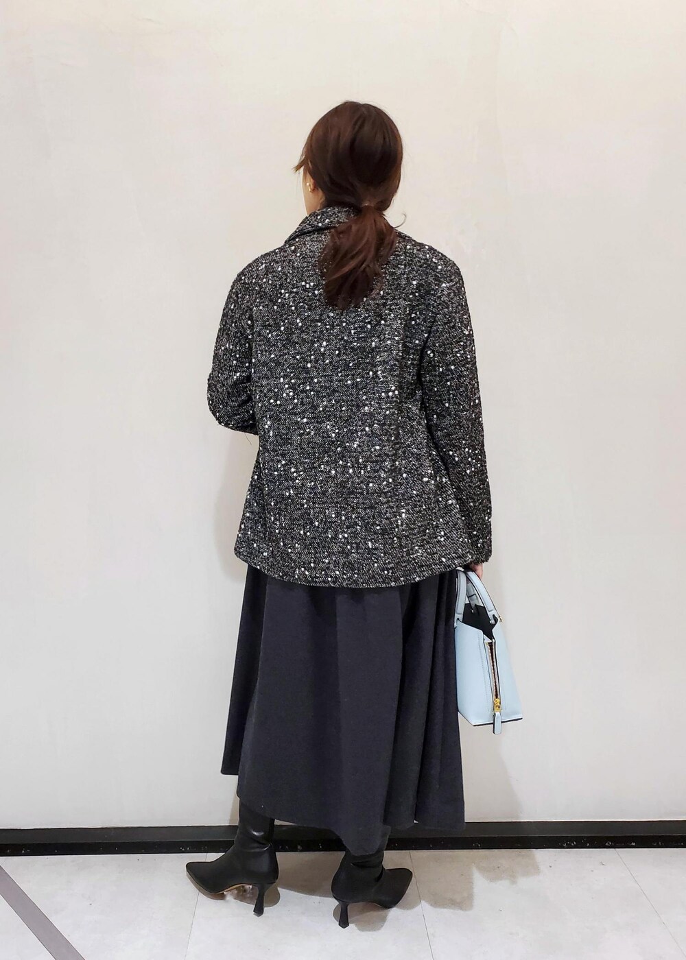 ブルー系のハンドバッグ、ブラック系のその他アウター、グレー系のワンピースを着用したレディースの冬コーディネートの3枚目の写真