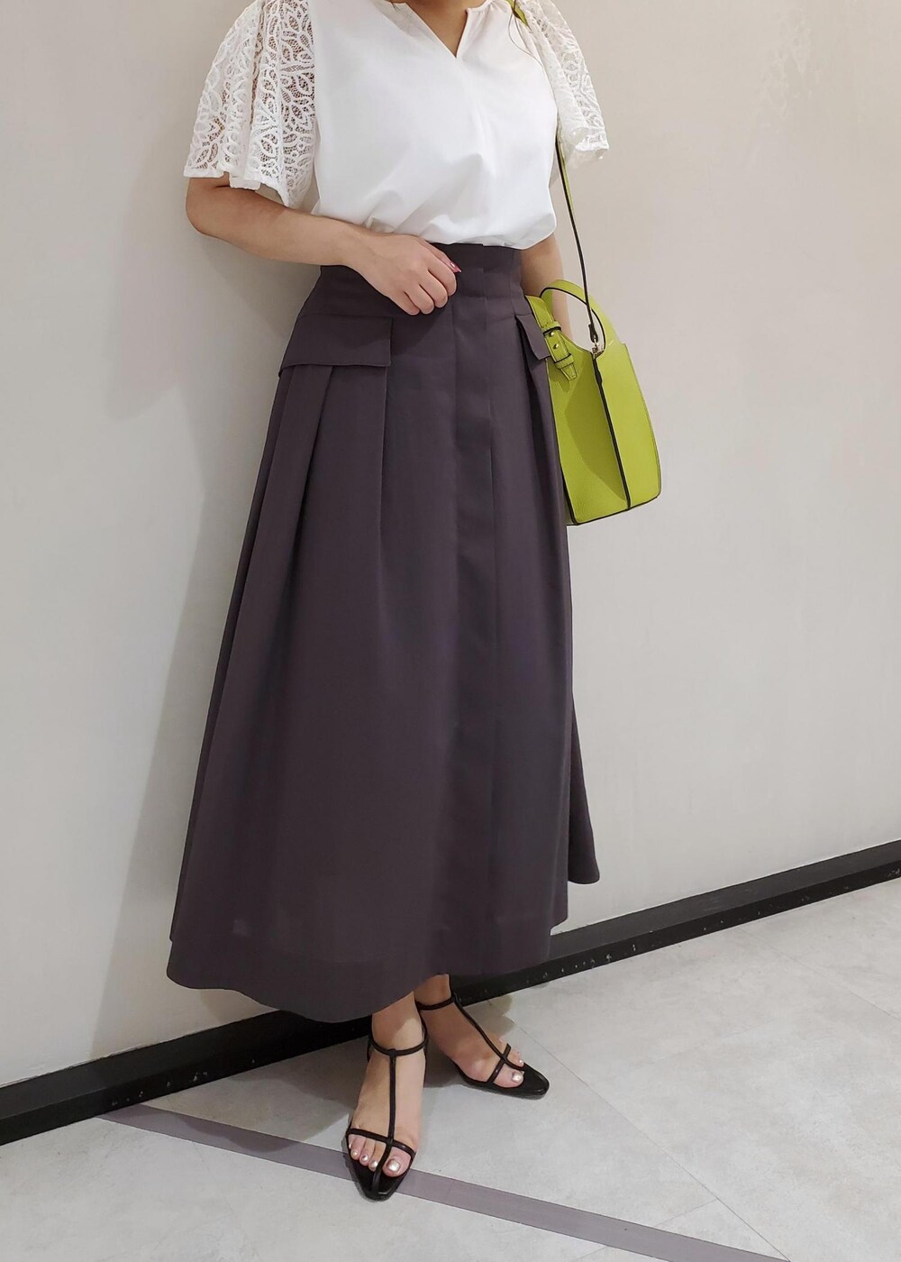 グリーン系のハンドバッグ、ブラック系のサンダル、ブラウン系のスカートを着用したレディースの夏コーディネートの5枚目の写真