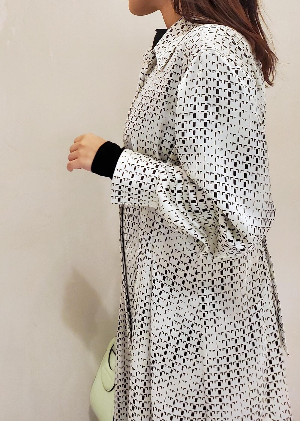 グリーン系のハンドバッグ、ホワイト系のスニーカー、ホワイト系のワンピースを着用したレディースの冬コーディネートの5枚目の写真