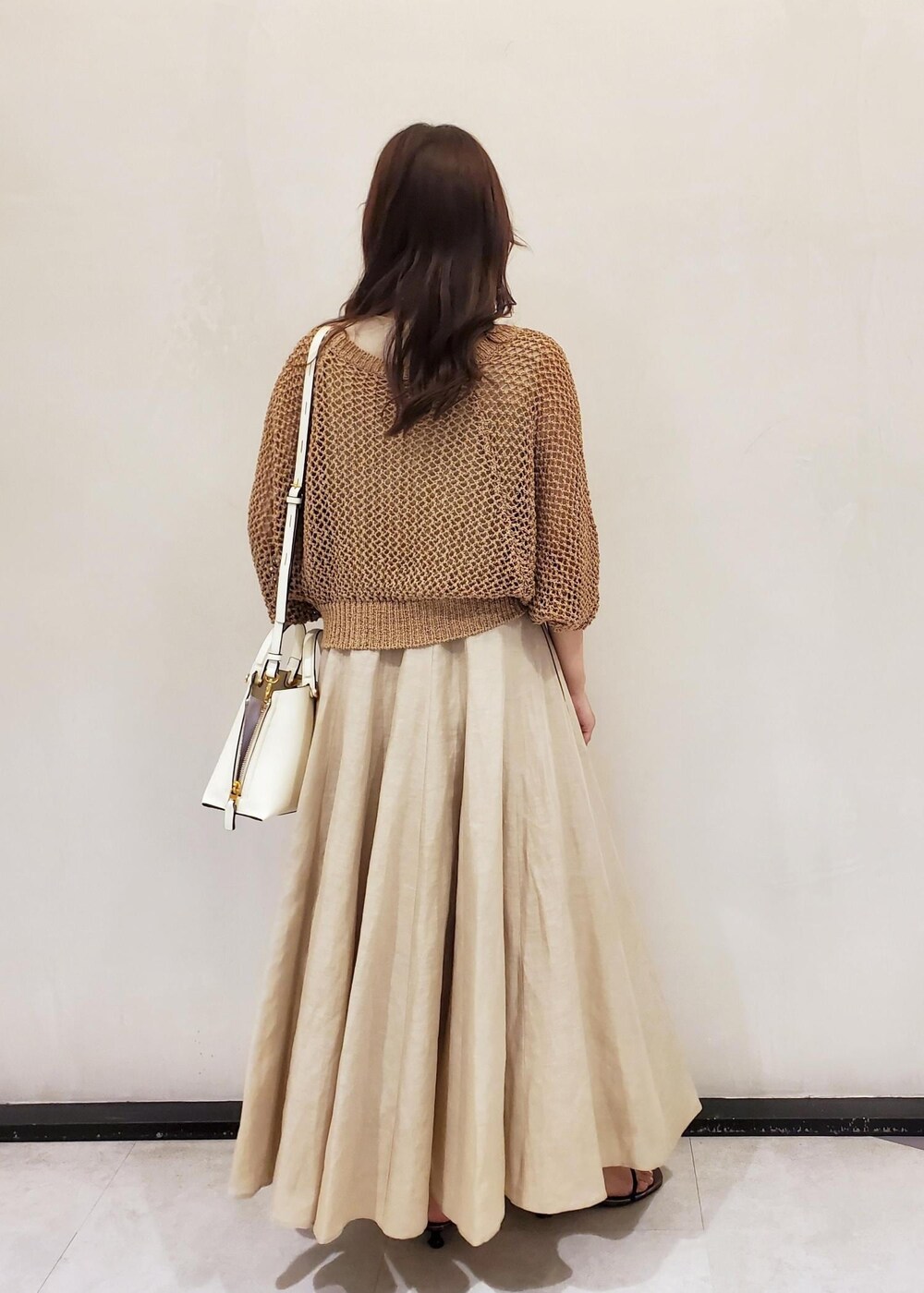 ホワイト系のハンドバッグ、ベージュ系のワンピース、ベージュ系のカーディガン/ボレロを着用したレディースの夏コーディネートの3枚目の写真