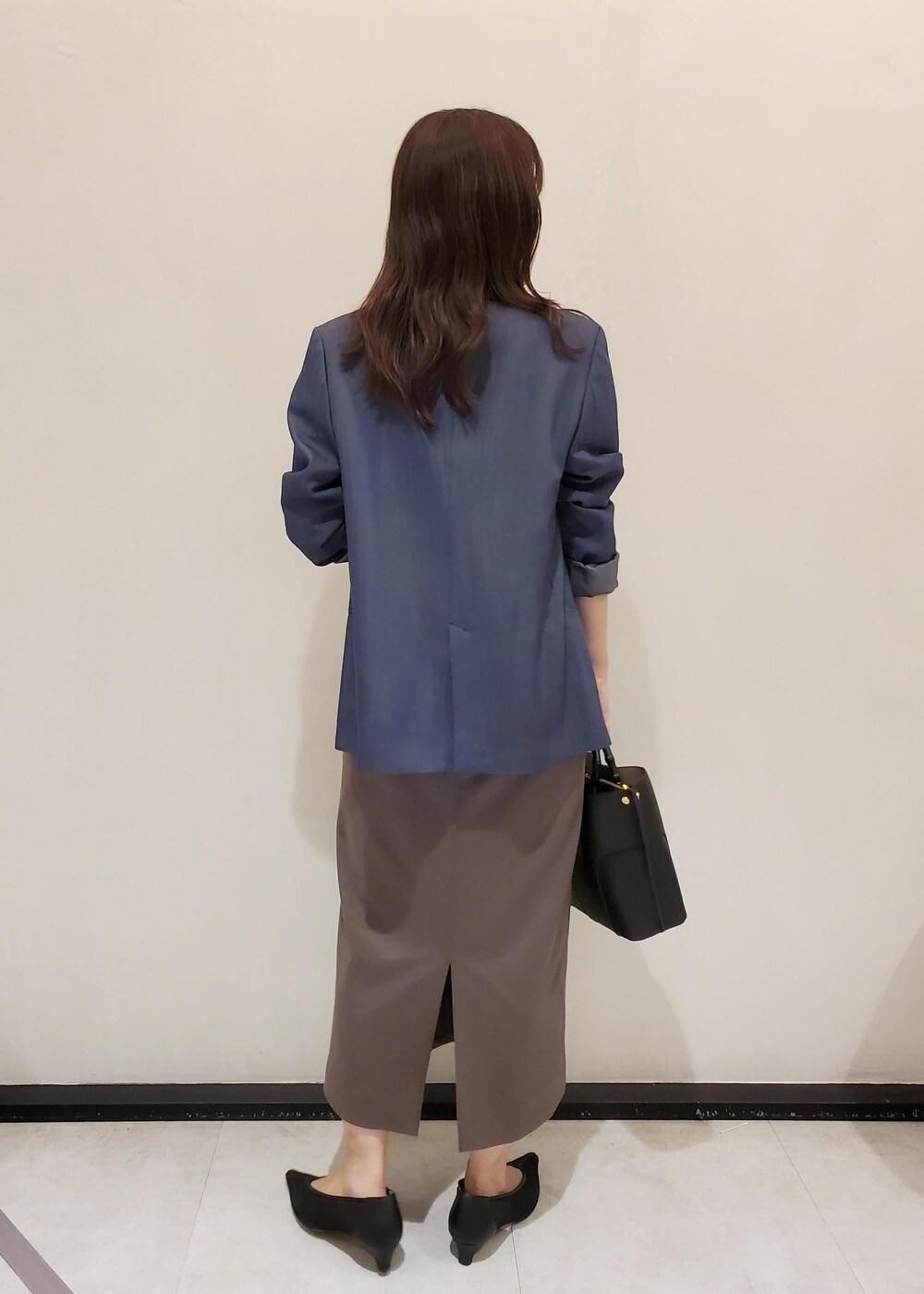 ブラック系のパンプス、ブルー系のテーラードジャケット、ブラック系のハンドバッグを着用したレディースの秋コーディネートの3枚目の写真