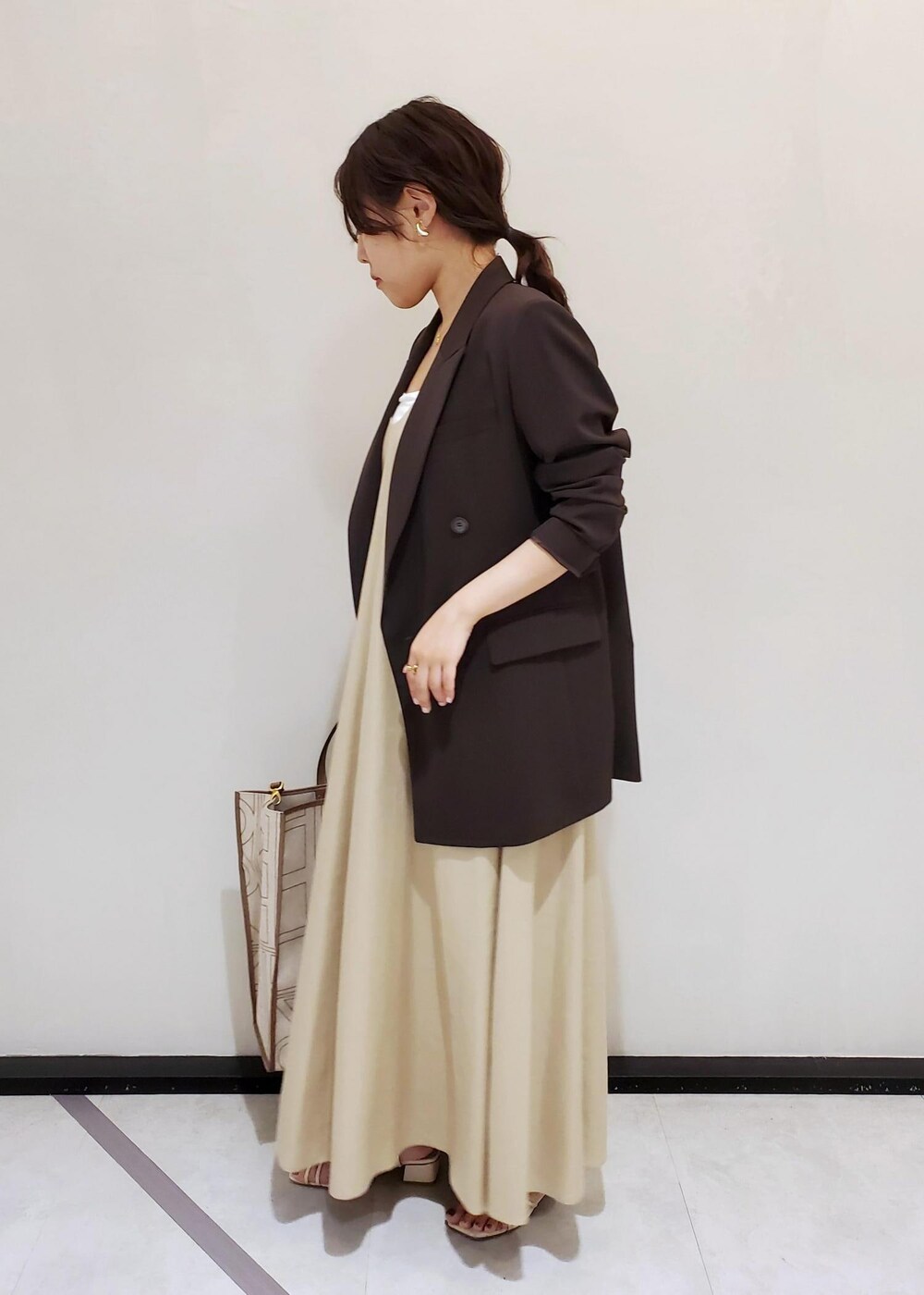 ブラウン系のテーラードジャケット、ベージュ系のワンピース、ゴールド系のネックレスを着用したレディースの春コーディネートの2枚目の写真