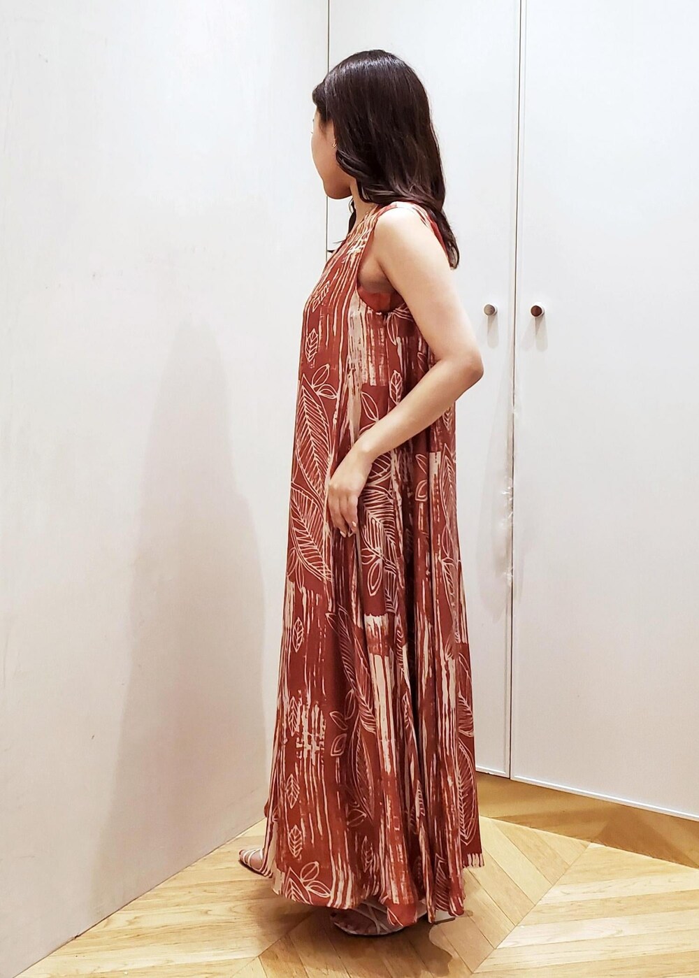 ブラウン系のワンピース、ホワイト系のショルダーバッグ、ゴールド系のネックレスを着用したレディースの夏コーディネートの2枚目の写真