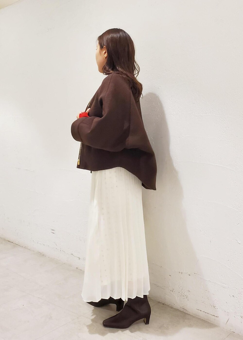 グレー系のハンドバッグ、ブラウン系のブーツ、ブラウン系のブルゾンを着用したレディースの秋コーディネートの2枚目の写真