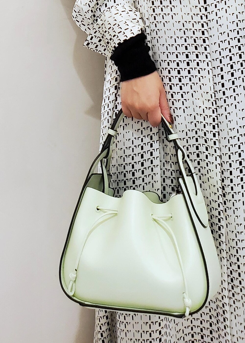 グリーン系のハンドバッグ、ホワイト系のスニーカー、ホワイト系のワンピースを着用したレディースの冬コーディネートの8枚目の写真