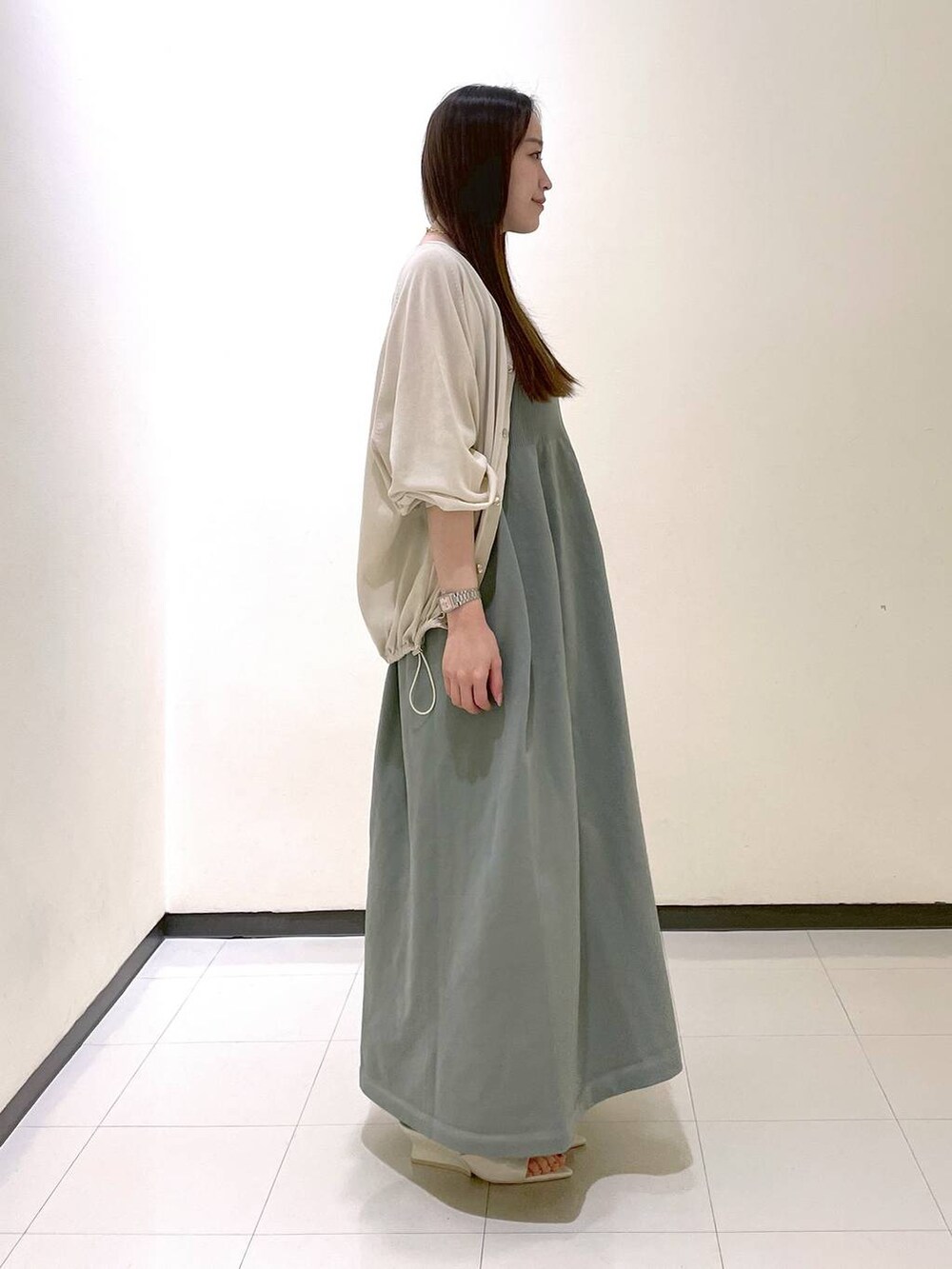 ホワイト系のサンダル、ホワイト系のカーディガン/ボレロ、グリーン系のワンピースを着用したレディースの夏コーディネートの2枚目の写真