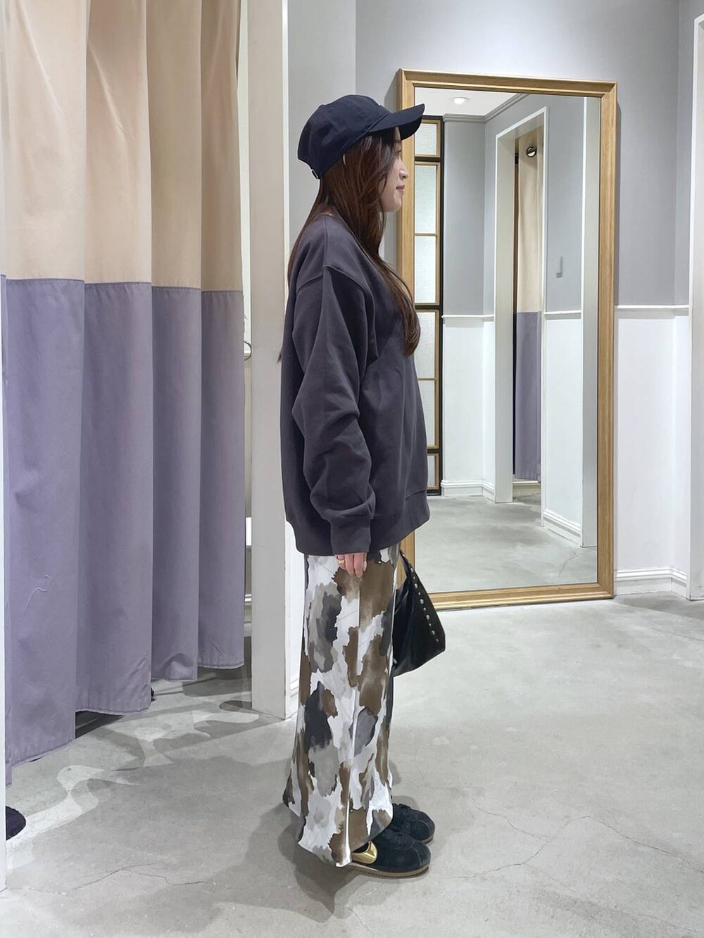 ブラック系のハンドバッグ、ブラウン系のスカート、グレー系のスウェットを着用したレディースの秋コーディネートの2枚目の写真