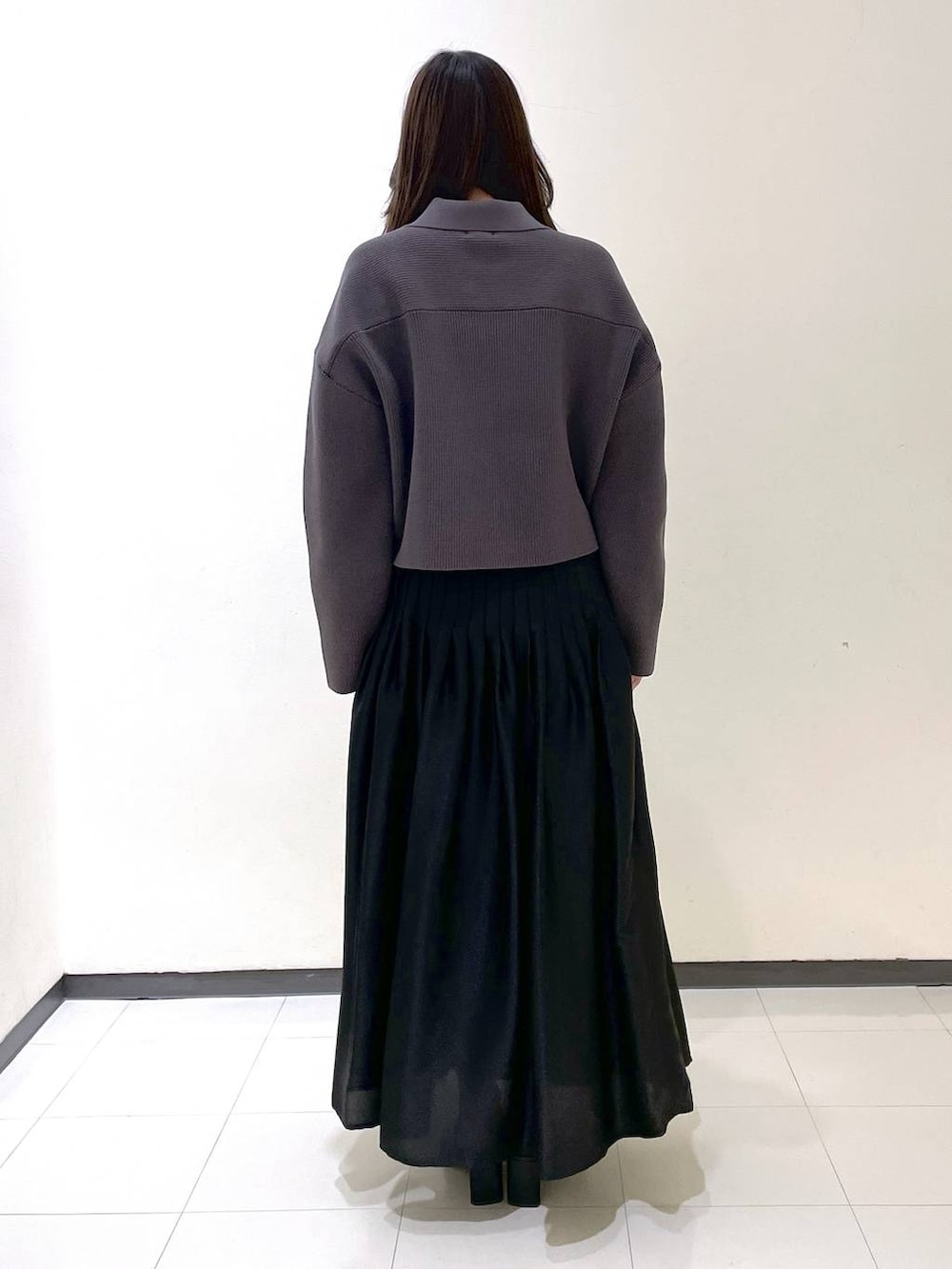 ブラック系のスカート、ブラック系のサンダル、グレー系のカーディガン/ボレロを着用したレディースの春コーディネートの3枚目の写真