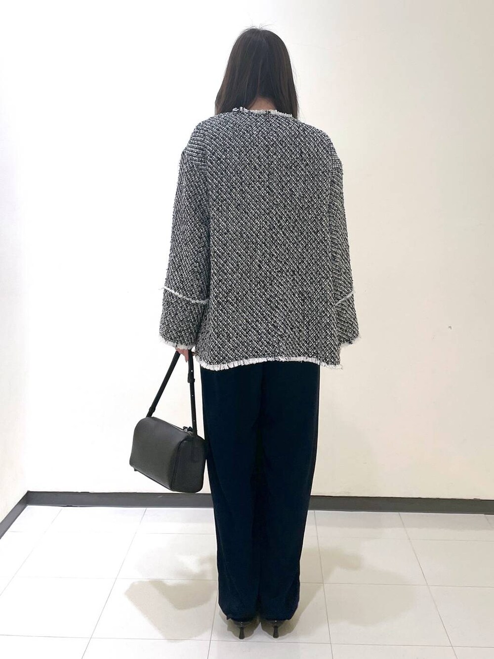 ブラック系のハンドバッグ、ブラック系のパンプス、ブラック系のノーカラージャケットを着用したレディースの春コーディネートの3枚目の写真