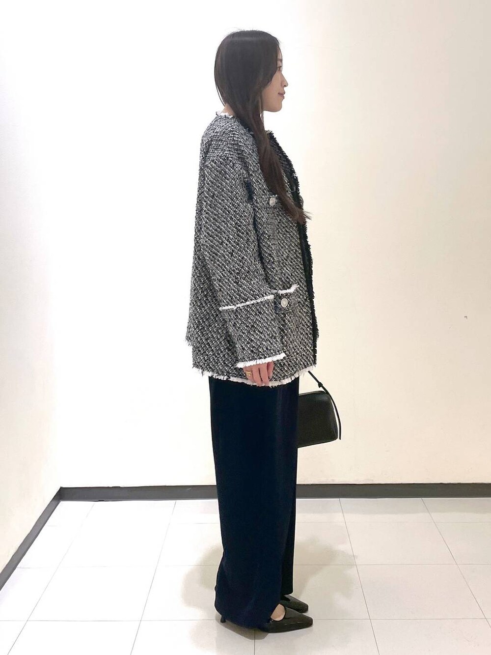 ブラック系のハンドバッグ、ブラック系のパンプス、ブラック系のノーカラージャケットを着用したレディースの春コーディネートの2枚目の写真