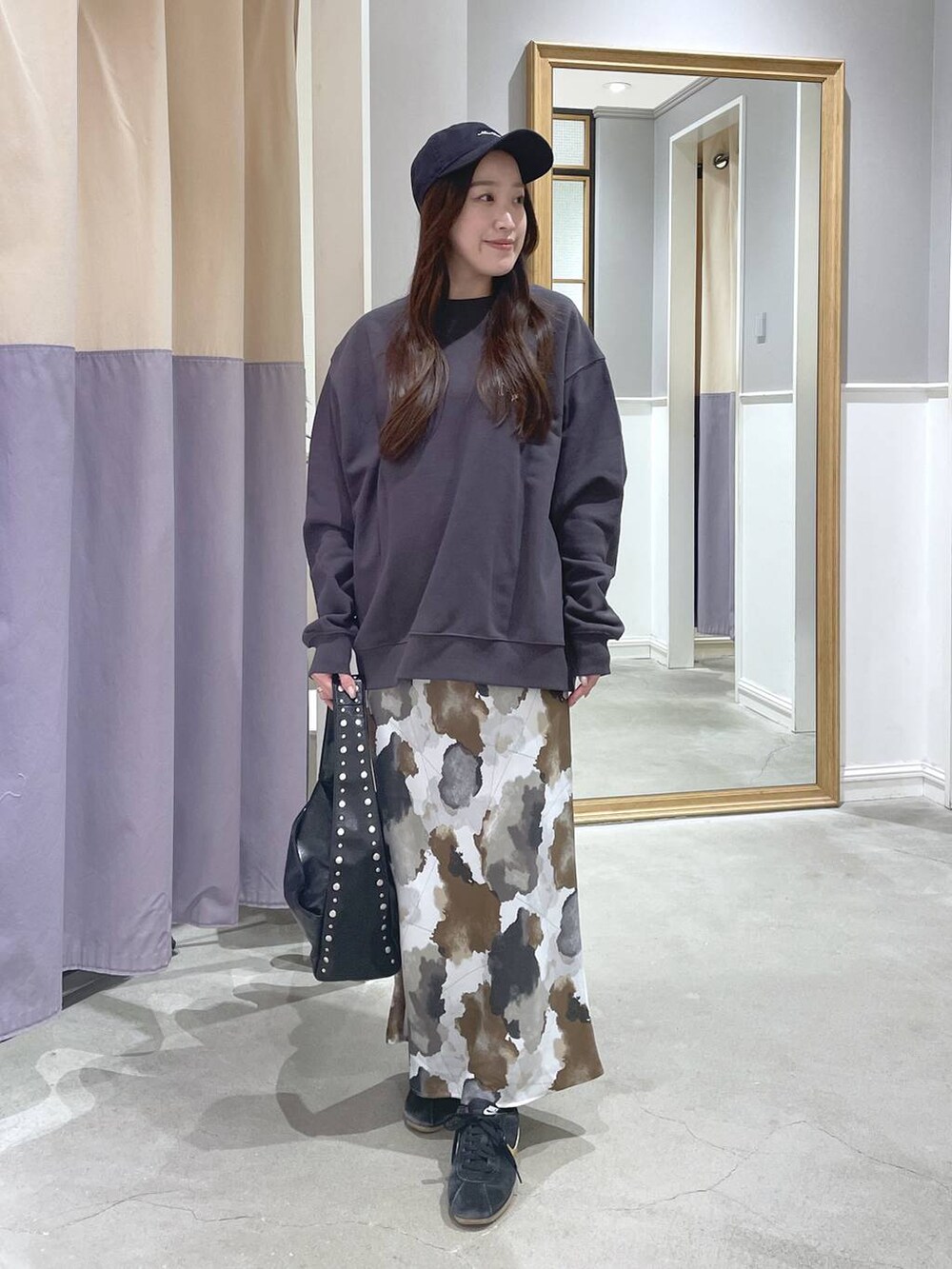 ブラック系のハンドバッグ、ブラウン系のスカート、グレー系のスウェットを着用したレディースの秋コーディネートの3枚目の写真