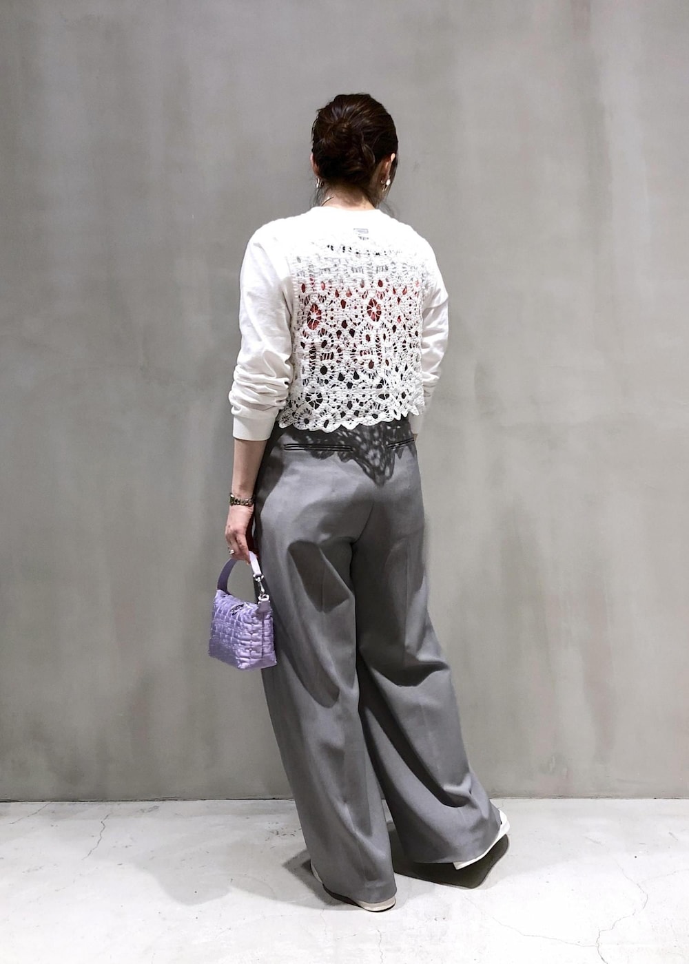 ホワイト系のベスト、パープル系のハンドバッグ、グレー系のスラックスを着用したレディースの冬コーディネートの3枚目の写真