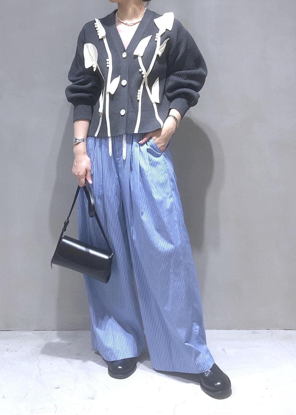 ブラック系のサンダル、グレー系のカーディガン/ボレロ、ブルー系のスラックスを着用したレディースの秋コーディネートの2枚目の写真