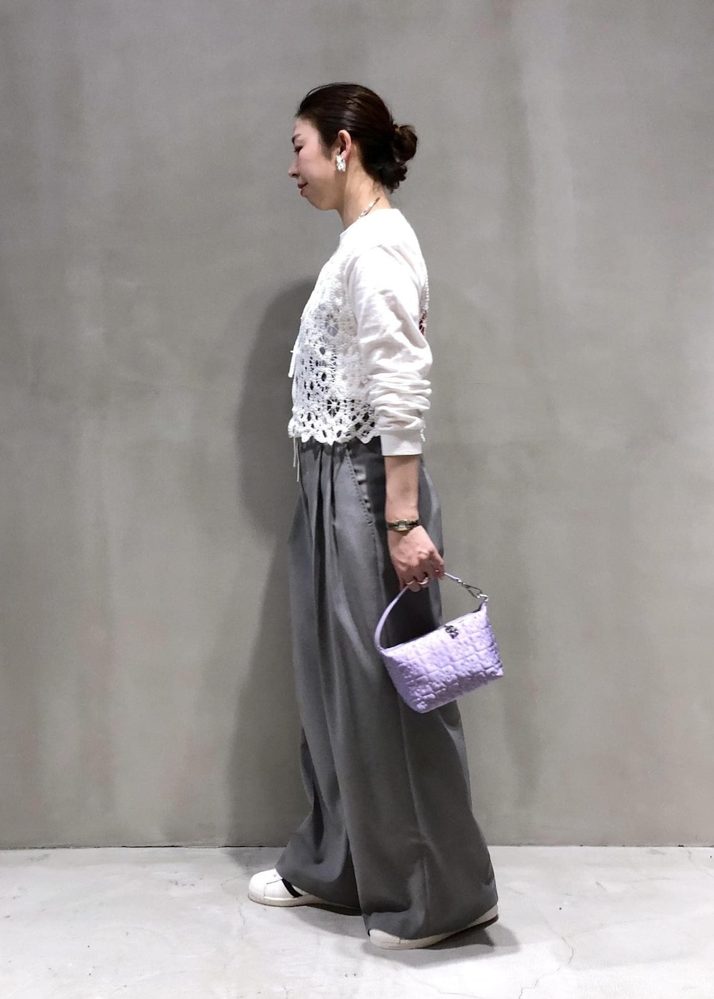 ホワイト系のベスト、パープル系のハンドバッグ、グレー系のスラックスを着用したレディースの冬コーディネートの2枚目の写真