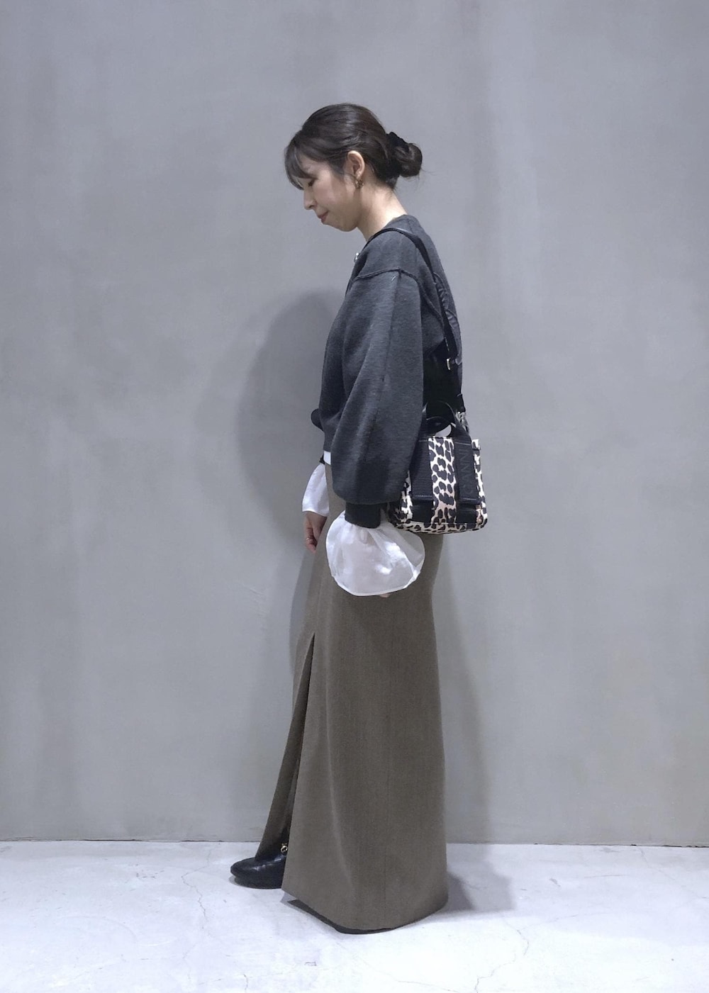 ベージュ系のスカート、グレー系のニット/セーターを着用したレディースの秋コーディネートの2枚目の写真