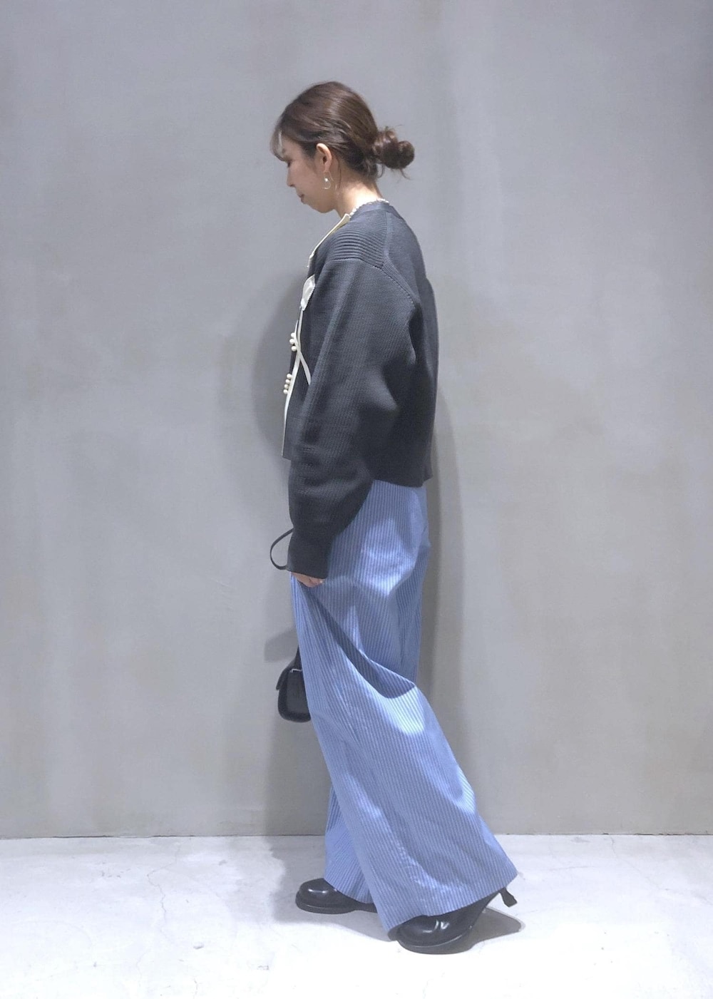 ブラック系のサンダル、グレー系のカーディガン/ボレロ、ブルー系のスラックスを着用したレディースの秋コーディネートの3枚目の写真