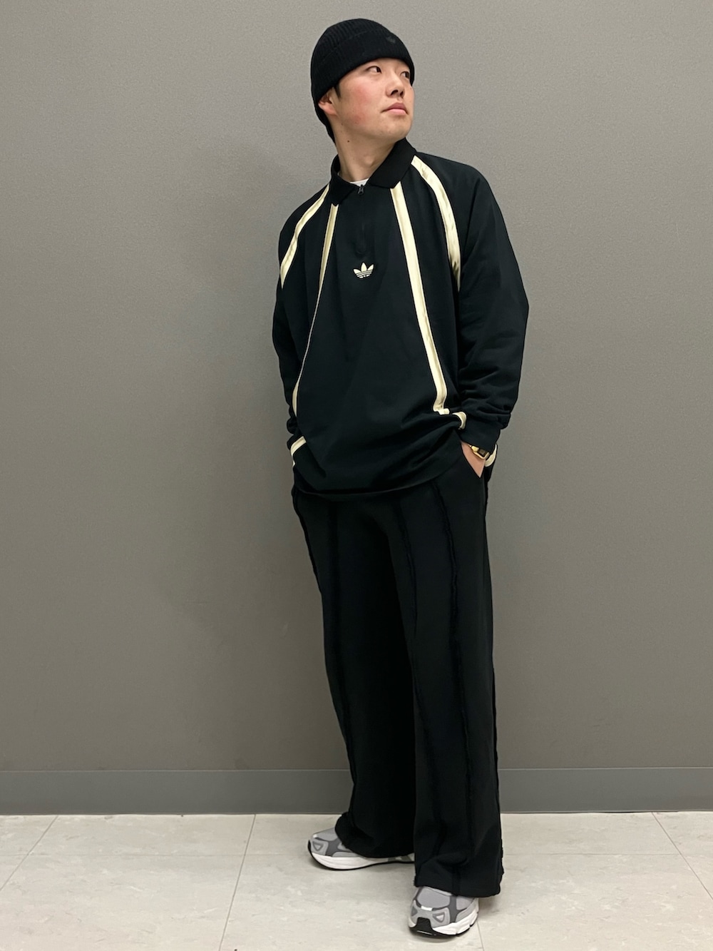 ブラック系のポロシャツ、グレー系のスニーカー、ブラック系のニットキャップ/ビーニーを着用したメンズの春コーディネートの2枚目の写真