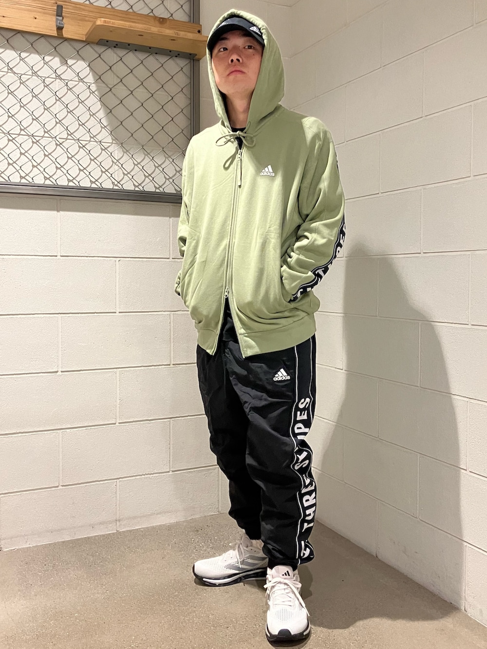 グリーン系のパーカー、ブラック系のその他パンツ、ブラック系のキャップを着用したメンズの秋コーディネートの3枚目の写真