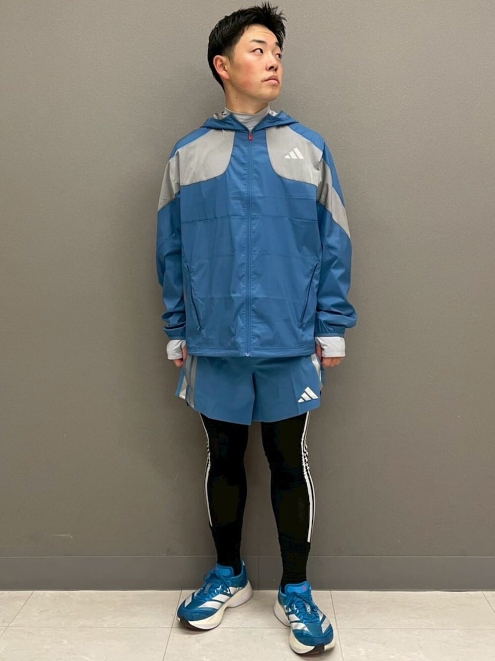 グレー系のトップス、ブルー系のシューズ、ブルー系のパンツを着用したメンズの冬コーディネートの2枚目の写真