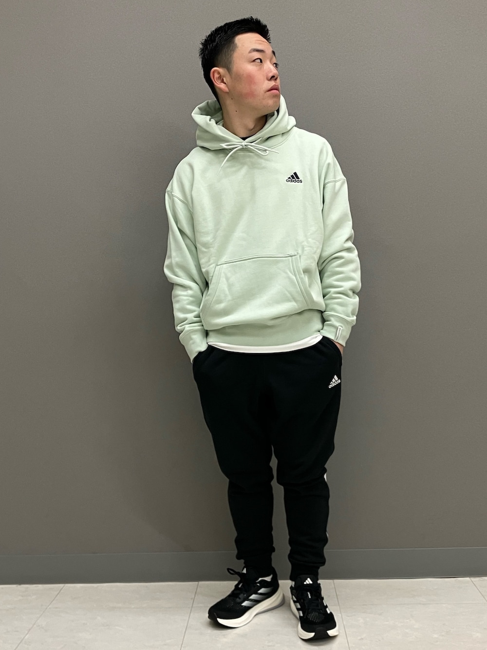 グリーン系のパーカー、ブラック系のスウェットパンツ、ブラック系のスニーカーを着用したメンズの春コーディネートの2枚目の写真