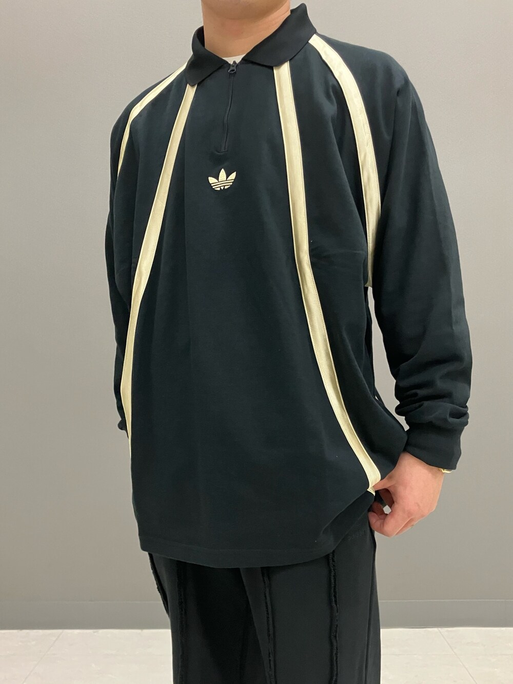 ブラック系のポロシャツ、グレー系のスニーカー、ブラック系のニットキャップ/ビーニーを着用したメンズの春コーディネートの3枚目の写真