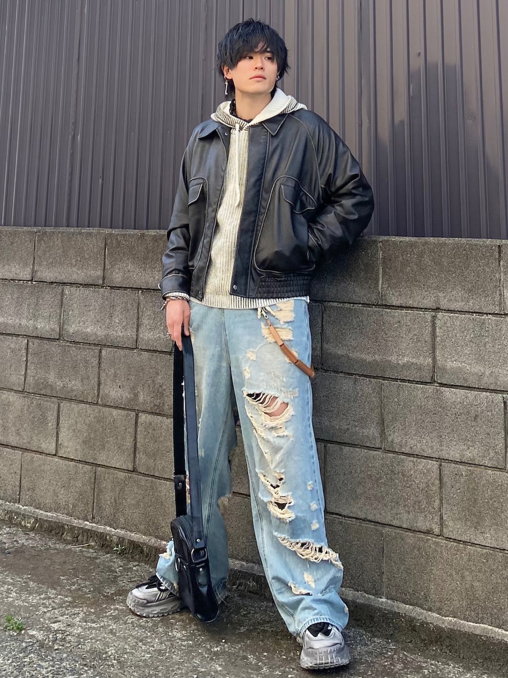 グレー系のブルゾン、ホワイト系のパーカー、ブルー系のデニムパンツを着用したメンズの春コーディネートの2枚目の写真