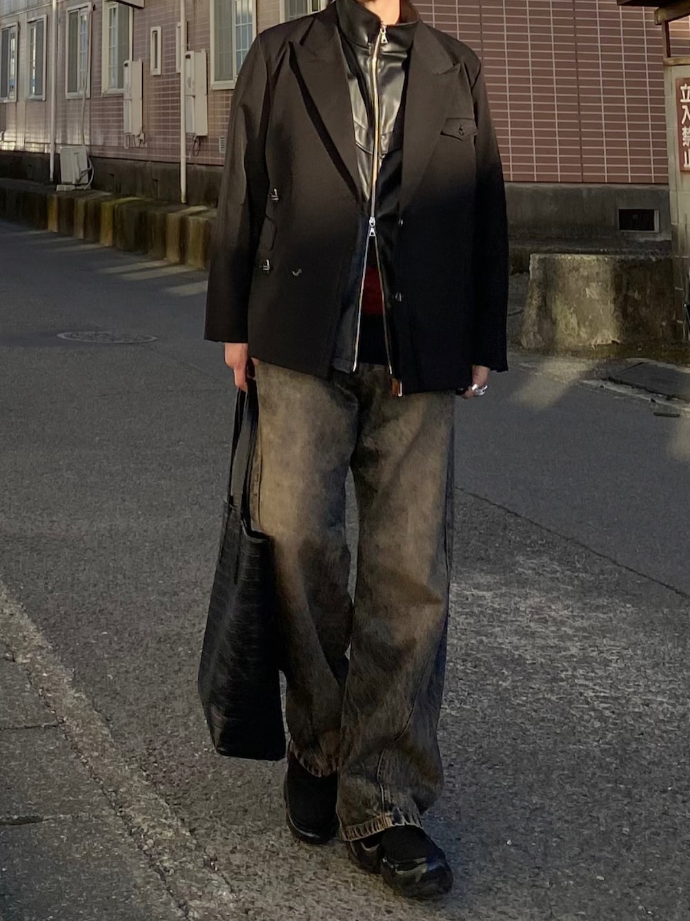 ブラック系のテーラードジャケット、ブラック系のベスト、レッド系のニット/セーターを着用したメンズの春コーディネートの3枚目の写真