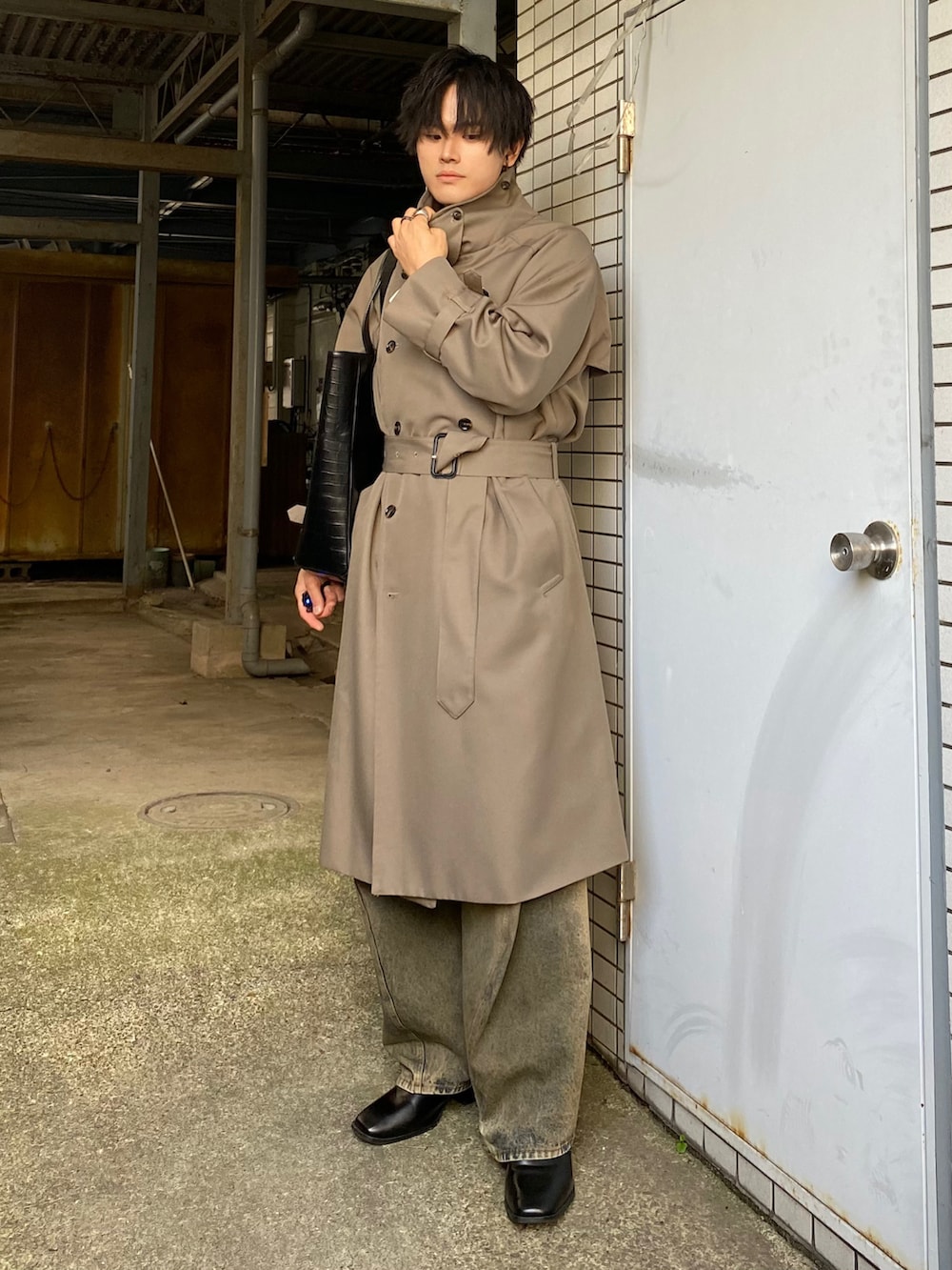 ベージュ系のトレンチコート、ブルー系のデニムパンツ、ブラック系のブーツを着用したメンズの秋コーディネートの2枚目の写真