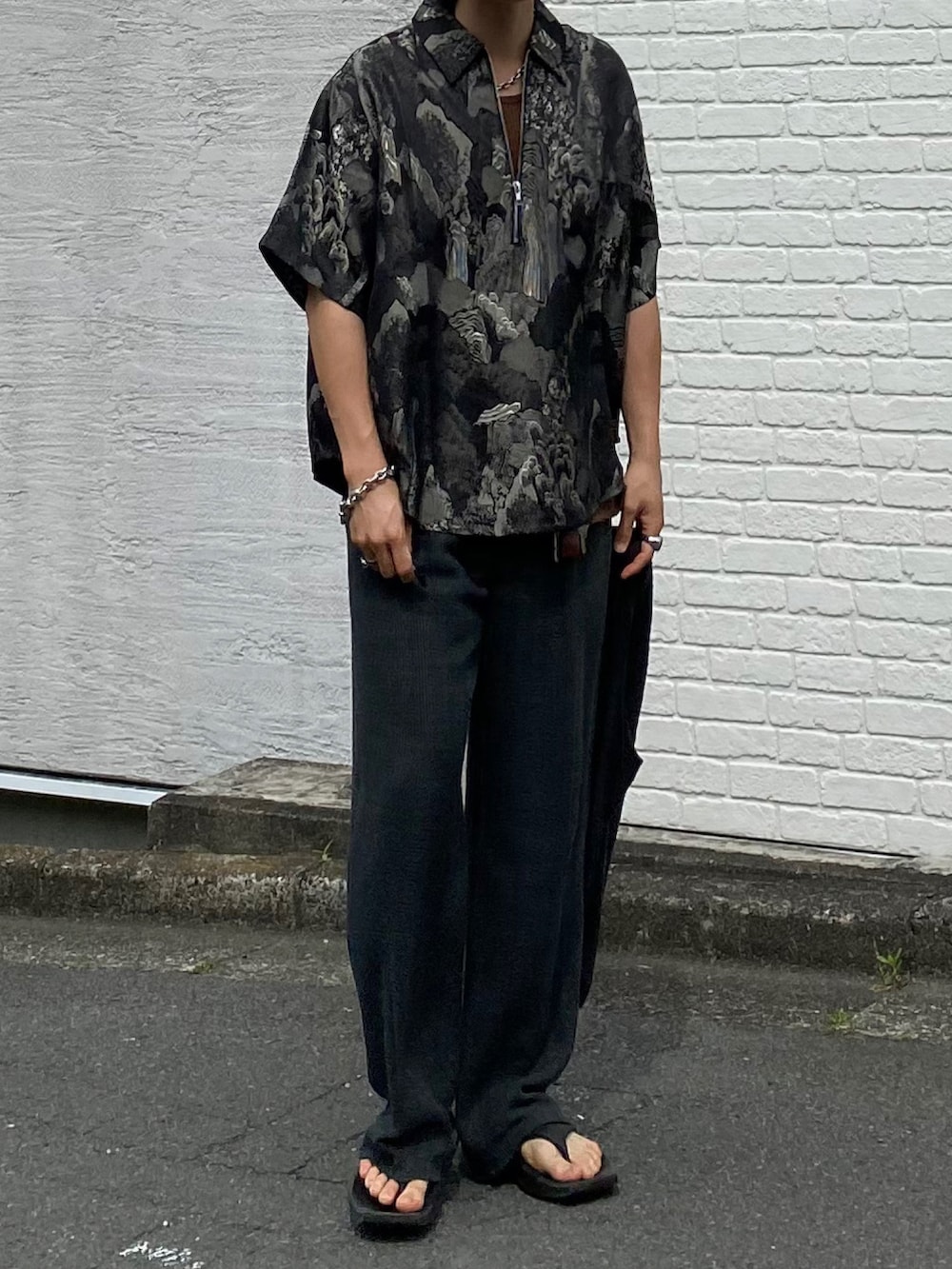 ブラック系のTシャツ/カットソー、ブラウン系のタンクトップ、グレー系のスラックスを着用したメンズの夏コーディネートの3枚目の写真