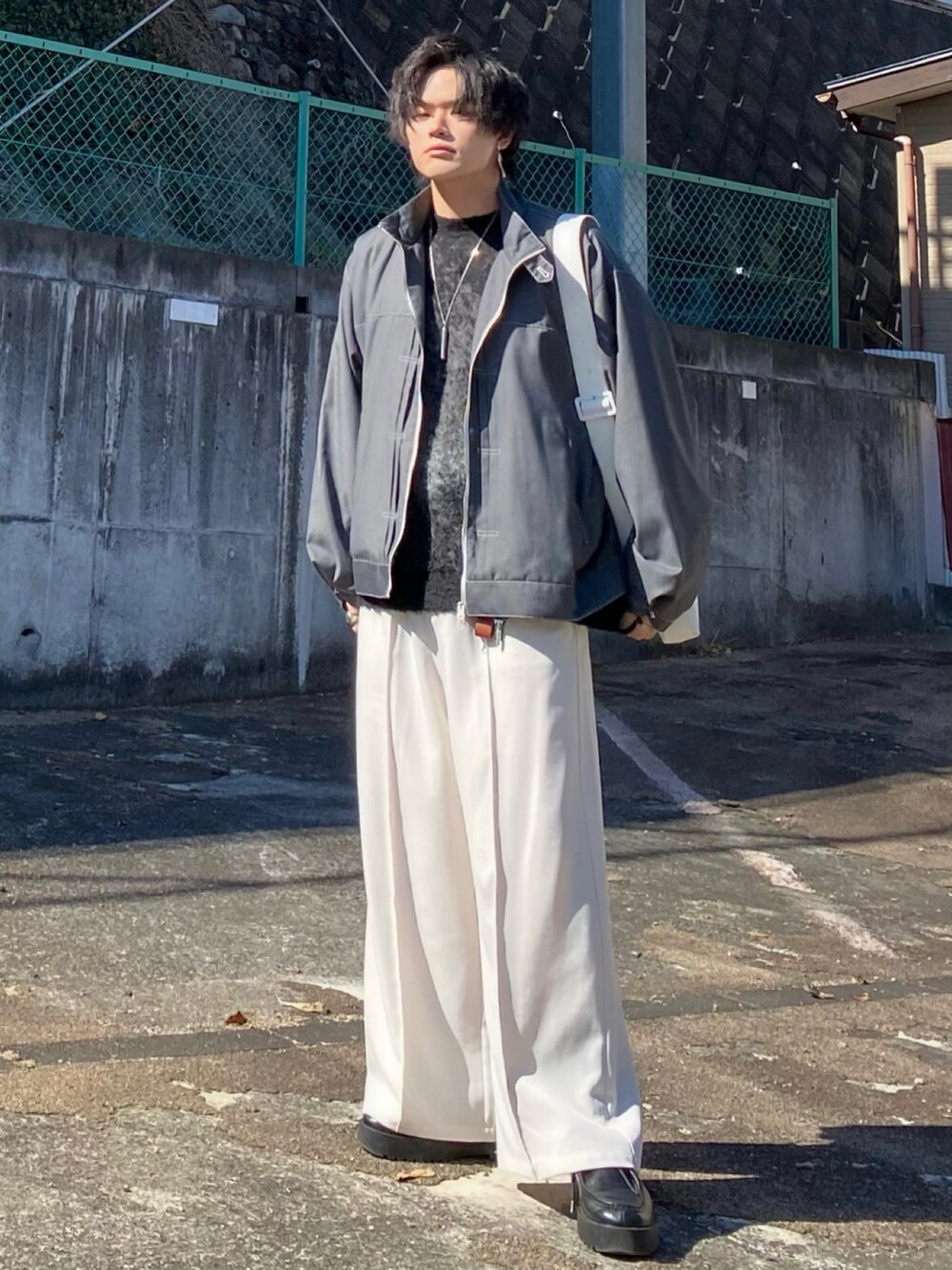 グレー系のブルゾン、グレー系のニット/セーター、ベージュ系のスラックスを着用したメンズの冬コーディネートの2枚目の写真