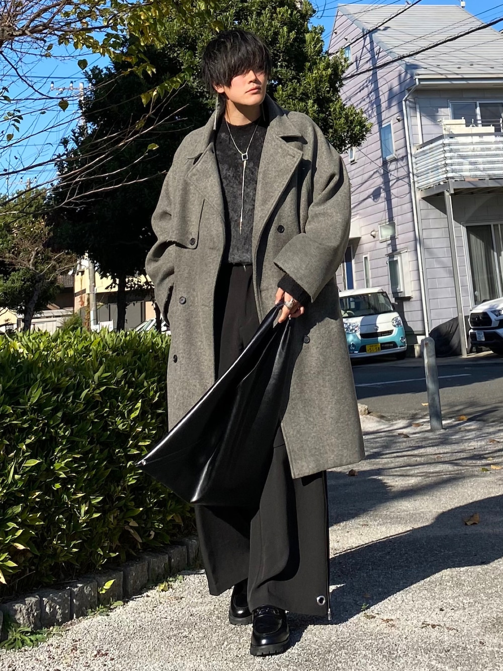 グレー系のトレンチコート、グレー系のニット/セーター、ブラック系のカーゴパンツを着用したメンズの冬コーディネートの2枚目の写真