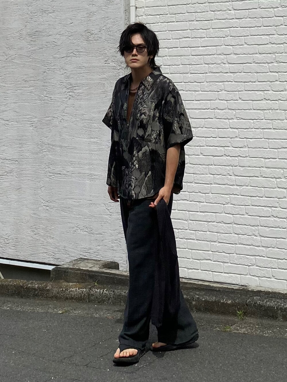 ブラック系のTシャツ/カットソー、ブラウン系のタンクトップ、グレー系のスラックスを着用したメンズの夏コーディネートの4枚目の写真