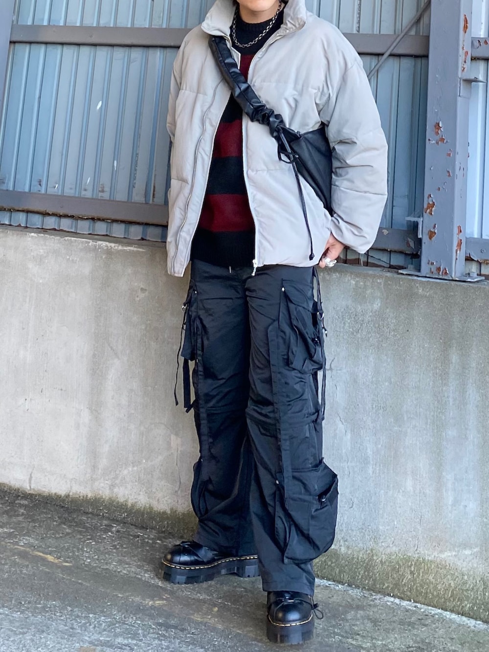 グレー系のダウンジャケット/コート、レッド系のニット/セーター、ブラック系のカーゴパンツを着用したメンズの冬コーディネートの4枚目の写真