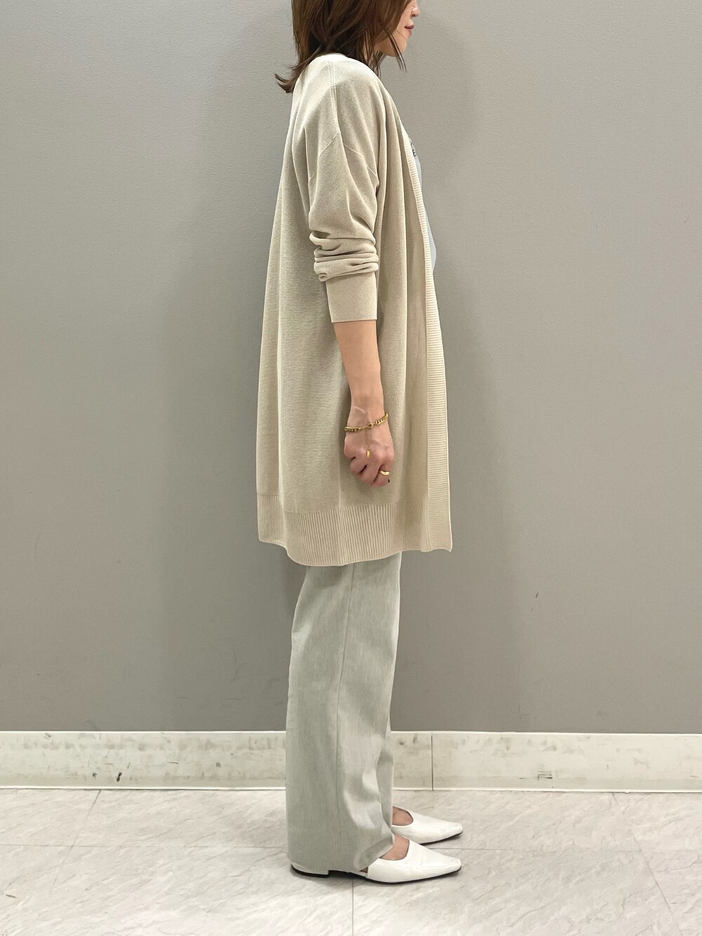 グリーン系のTシャツ/カットソー、ベージュ系のカーディガン/ボレロ、グレー系のスーツパンツを着用したレディースの春コーディネートの3枚目の写真