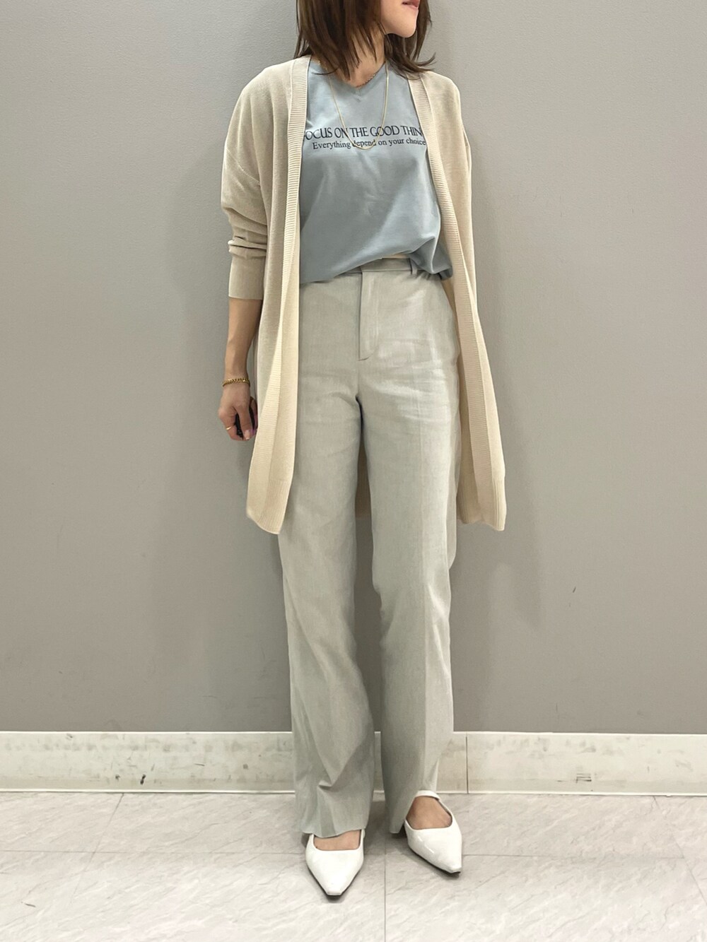 グリーン系のTシャツ/カットソー、ベージュ系のカーディガン/ボレロ、グレー系のスーツパンツを着用したレディースの春コーディネートの2枚目の写真