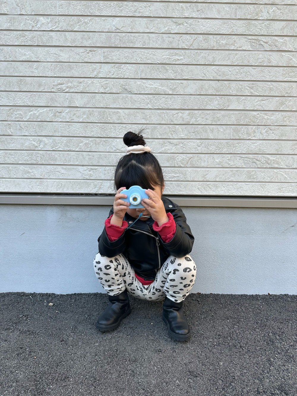 ブラック系のライダースジャケット、レッド系のスウェット、ブラック系のブーツを着用したキッズの春コーディネートの3枚目の写真