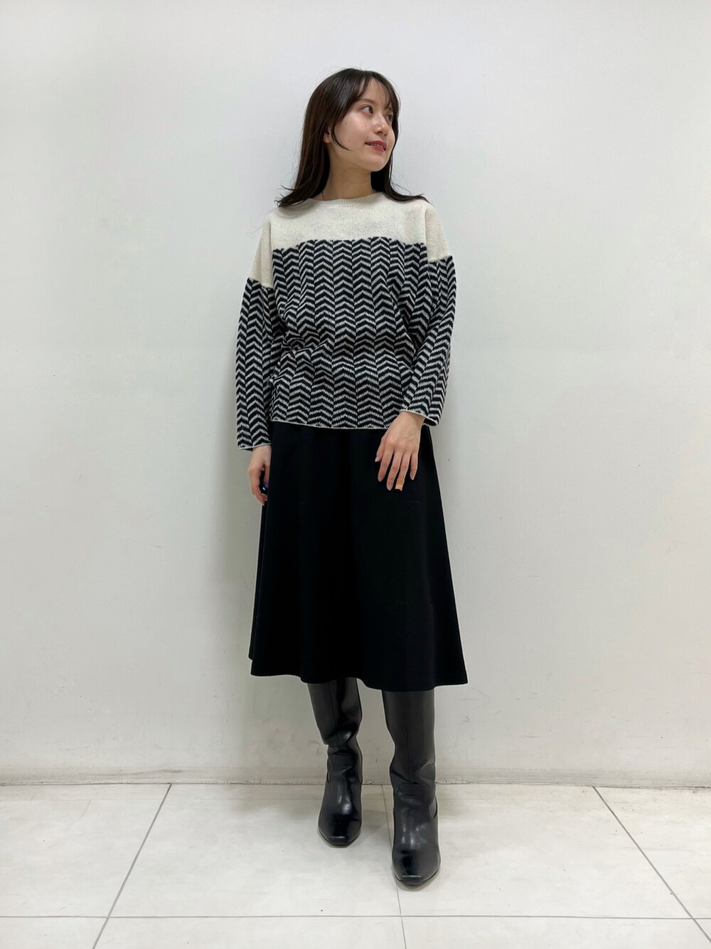 ホワイト系のニット/セーター、ブラック系のスカート、ブラック系のブーツを着用したレディースの秋コーディネートの4枚目の写真