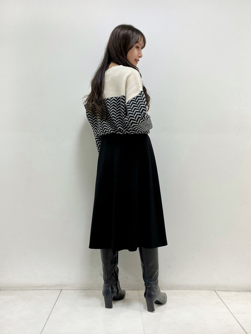 ホワイト系のニット/セーター、ブラック系のスカート、ブラック系のブーツを着用したレディースの秋コーディネートの3枚目の写真