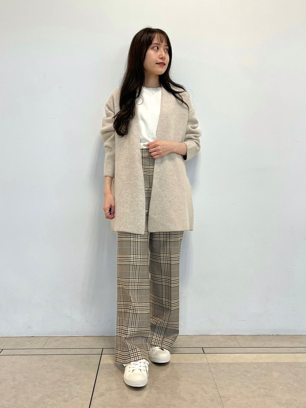 ベージュ系のカーディガン/ボレロ、ホワイト系のニット/セーター、ホワイト系のスニーカーを着用したレディースの秋コーディネートの2枚目の写真