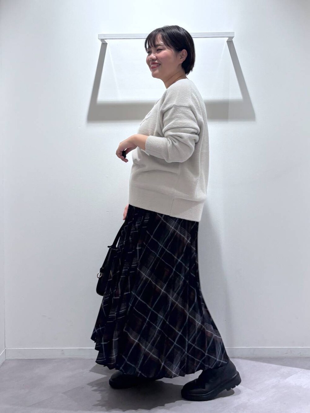 ブラック系のトートバッグ、ブラック系のブーツ、グレー系のニット/セーターを着用したレディースの秋コーディネートの2枚目の写真