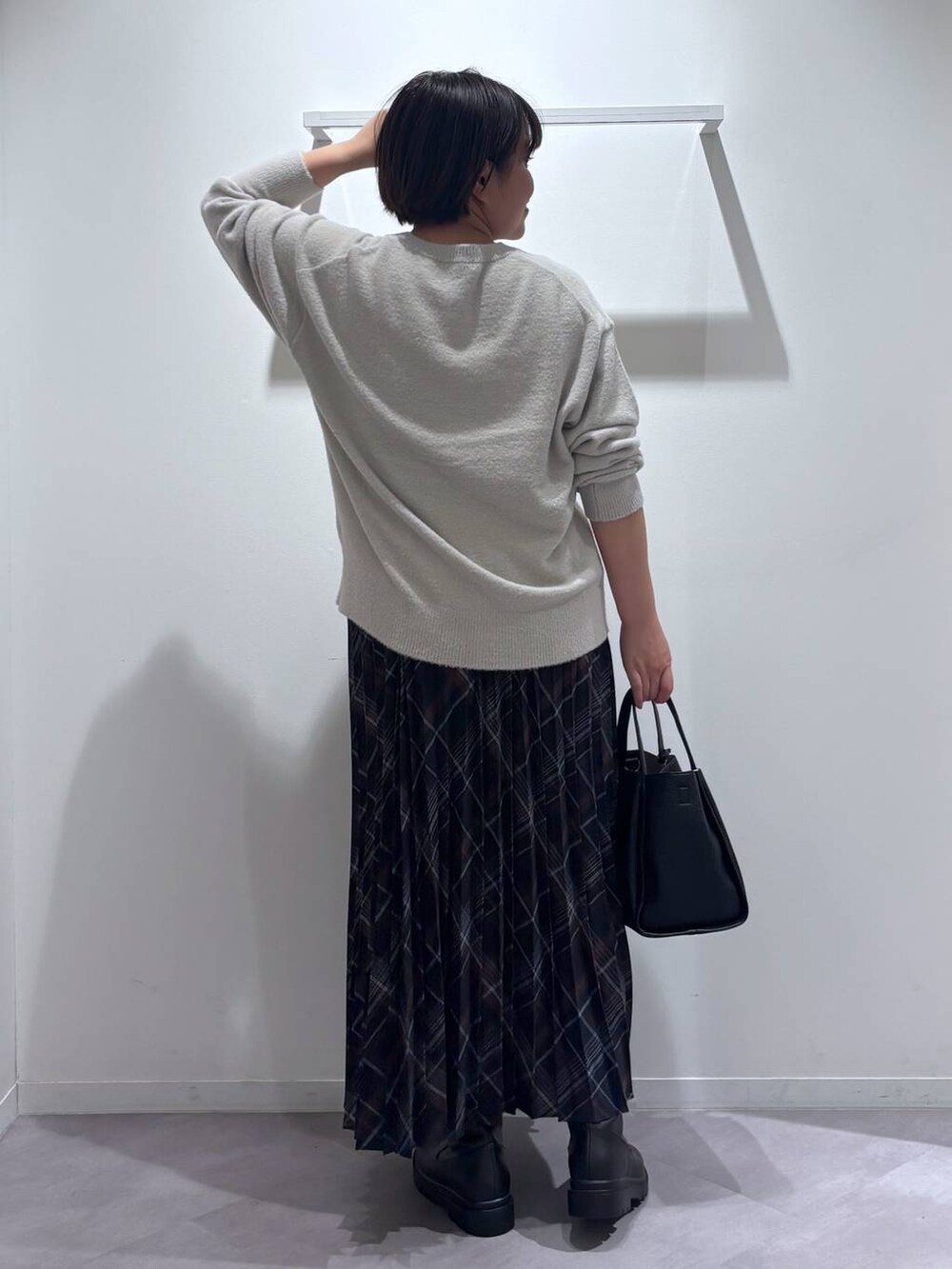 ブラック系のトートバッグ、ブラック系のブーツ、グレー系のニット/セーターを着用したレディースの秋コーディネートの3枚目の写真