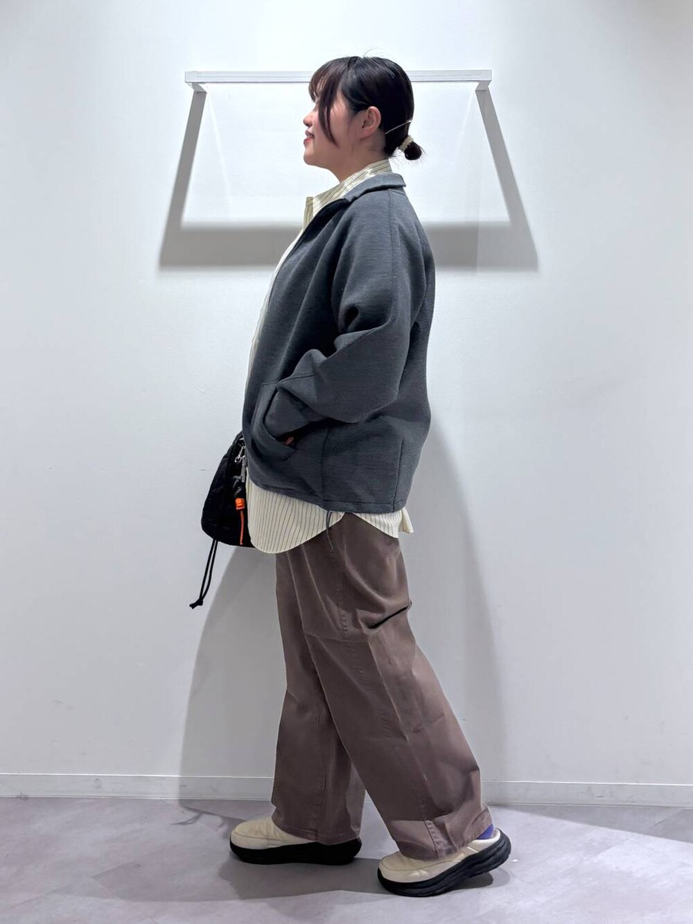 ブラック系のハンドバッグ、ブラウン系のデニムパンツ、ベージュ系のその他シューズを着用したレディースの春コーディネートの2枚目の写真