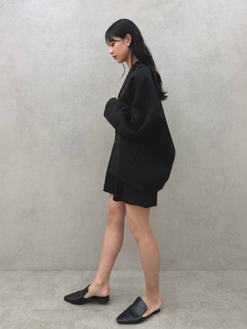 ブラック系のパンプス、ブラック系のノーカラージャケット、ブラック系のその他パンツを着用したレディースの冬コーディネートの2枚目の写真