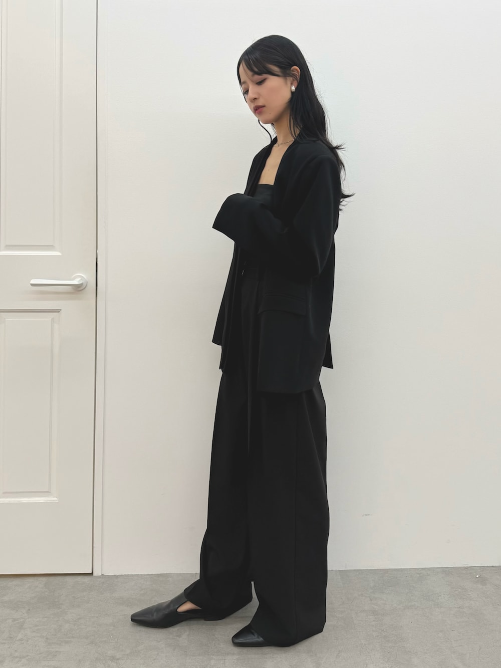 ブラック系のパンプス、ブラック系のノーカラージャケット、ブラック系のキャミソールを着用したレディースの冬コーディネートの2枚目の写真