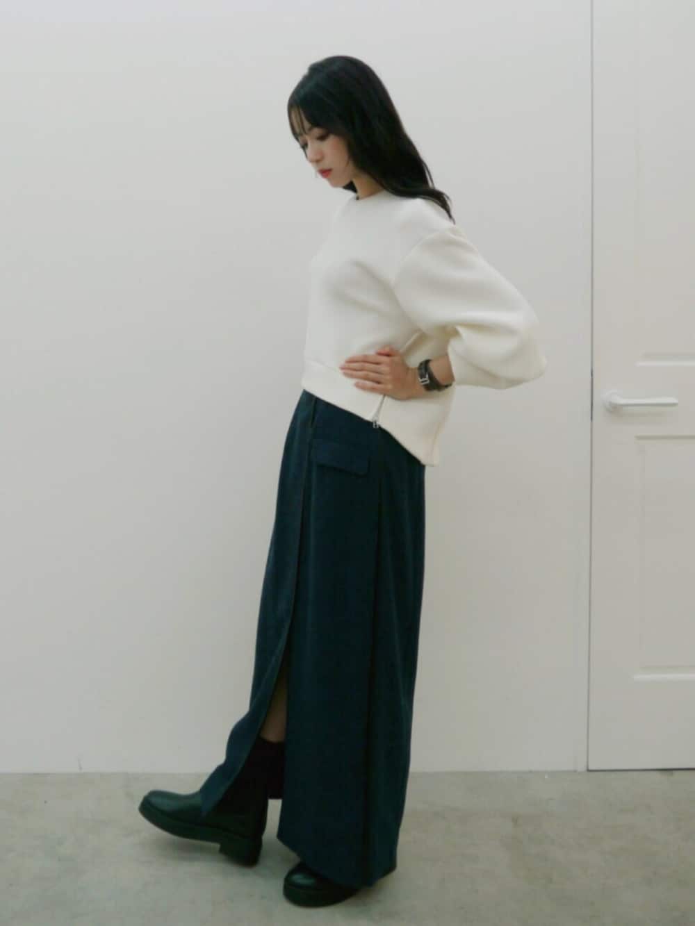 ホワイト系のスウェット、ブルー系のスカート、ブラック系のブーツを着用したレディースの秋コーディネートの2枚目の写真