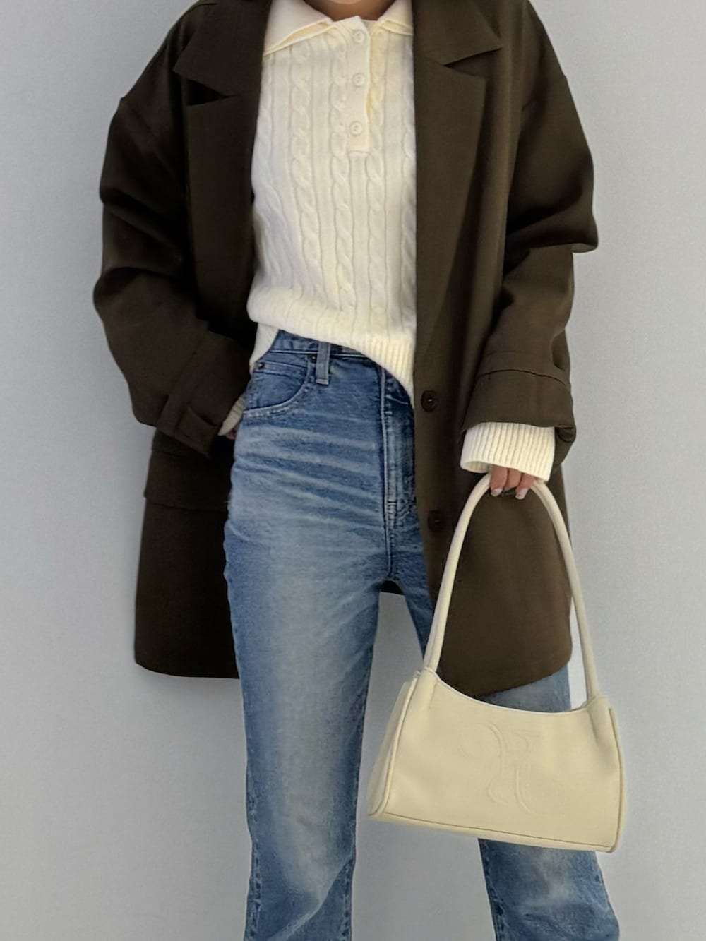 ブラック系のテーラードジャケット、ブラック系のブーツ、ベージュ系のトップスを着用したレディースの秋コーディネートの2枚目の写真