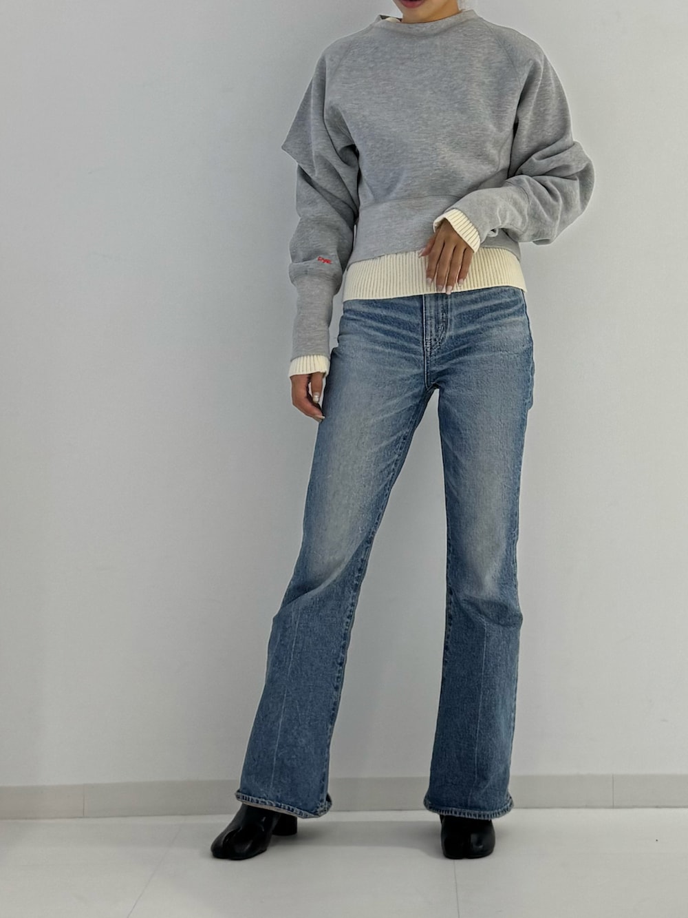 グレー系のスウェット、ブラック系のブーツ、ベージュ系のトップスを着用したレディースの秋コーディネートの2枚目の写真