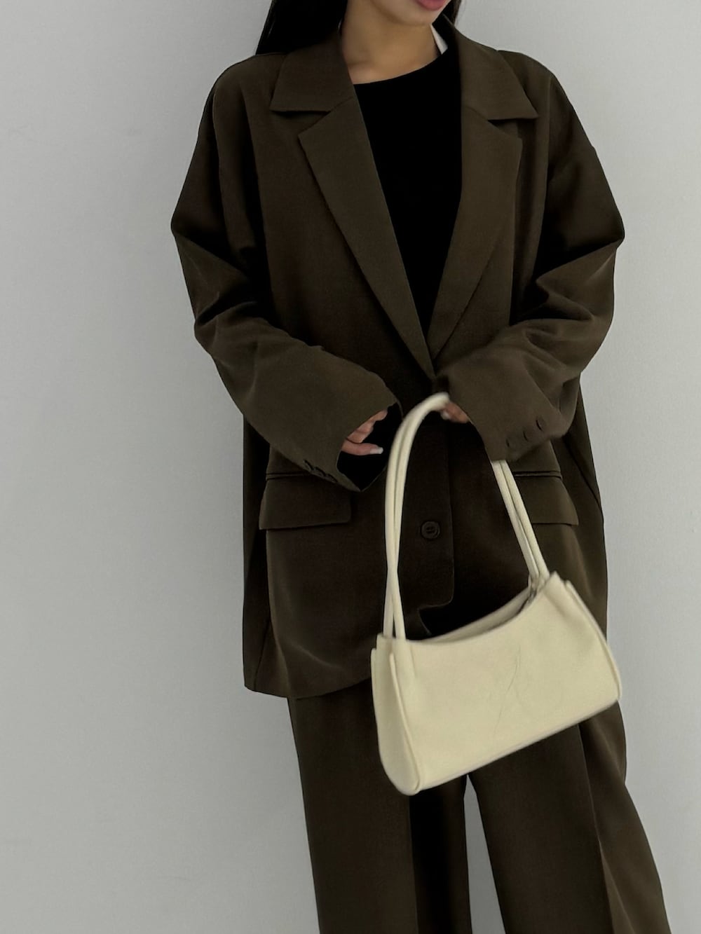 ブラック系のTシャツ/カットソー、ブラック系のテーラードジャケット、ブラウン系のスラックスを着用したレディースの秋コーディネートの4枚目の写真