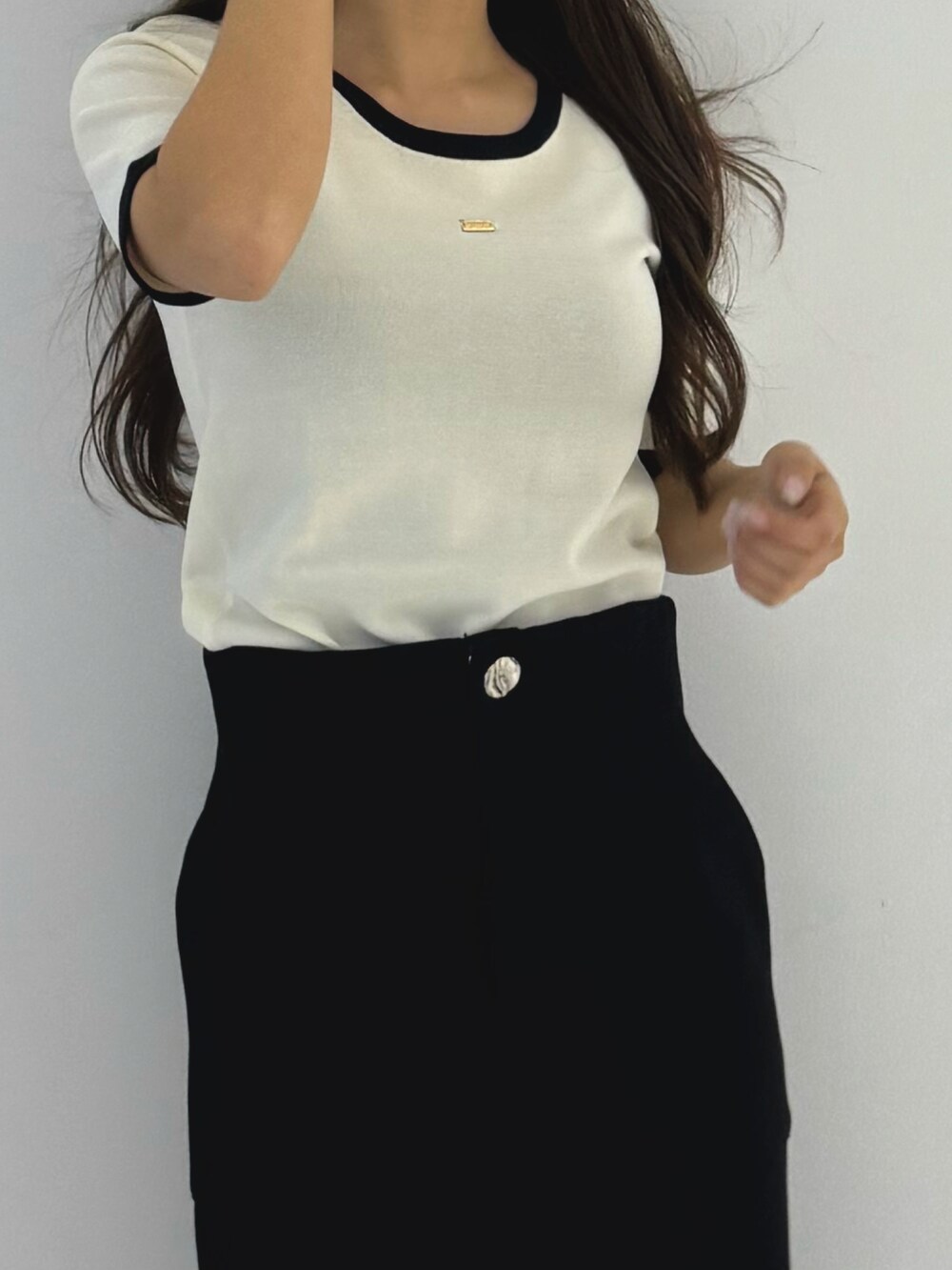 ブラック系のスカート、ホワイト系のトップス、ブラック系のローファーを着用したレディースの春コーディネートの3枚目の写真